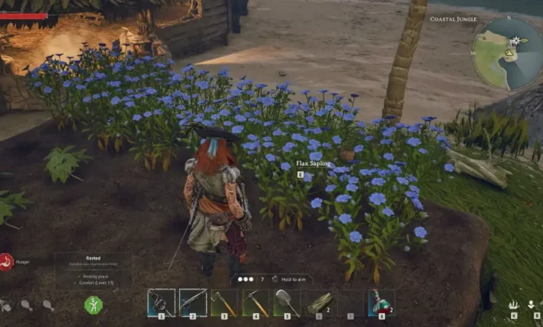 A video game character stands before a row of vibrant blue flax flowers in a tropical coastal jungle environment.