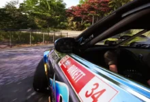 A side-angle view of a sponsored drift car sliding through a scenic, tree-lined curve during a high-speed race.