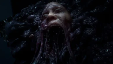 A distorted human face with a wide-open mouth is embedded within a dark, bulbous, and slimy organic mass.