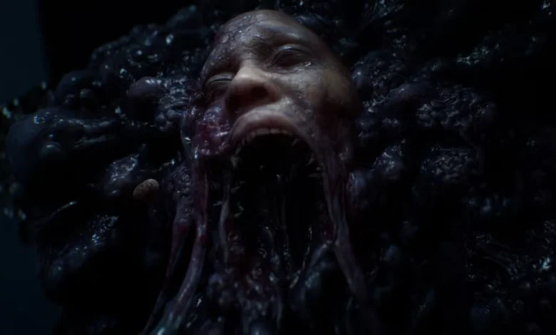 A distorted human face with a wide-open mouth is embedded within a dark, bulbous, and slimy organic mass.