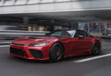 A sleek metallic red sports car speeds along an urban highway, with the background blurred to convey motion.