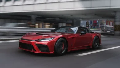 A sleek metallic red sports car speeds along an urban highway, with the background blurred to convey motion.