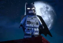 A LEGO Batman minifigure stands heroically on a rooftop against a backdrop of a large full moon and a starry night sky.