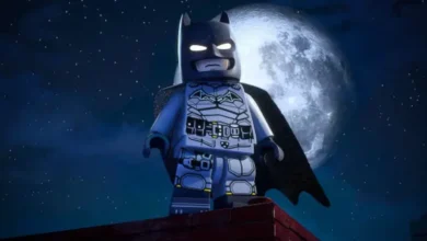 A LEGO Batman minifigure stands heroically on a rooftop against a backdrop of a large full moon and a starry night sky.