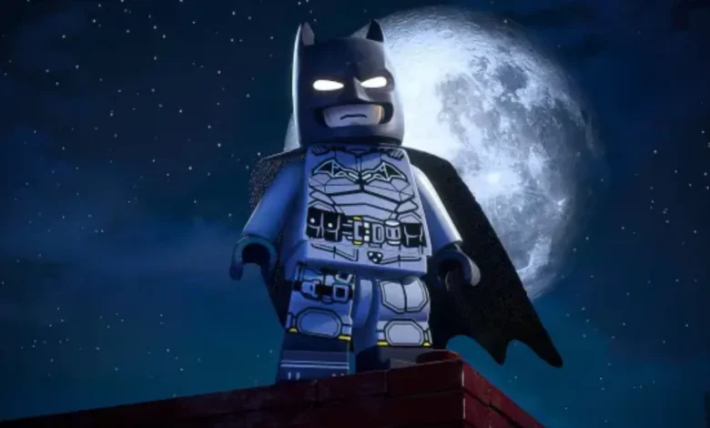 A LEGO Batman minifigure stands heroically on a rooftop against a backdrop of a large full moon and a starry night sky.