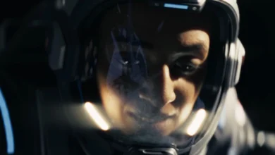 Close-up of an astronaut's focused face seen through the reflective visor of a futuristic space helmet.