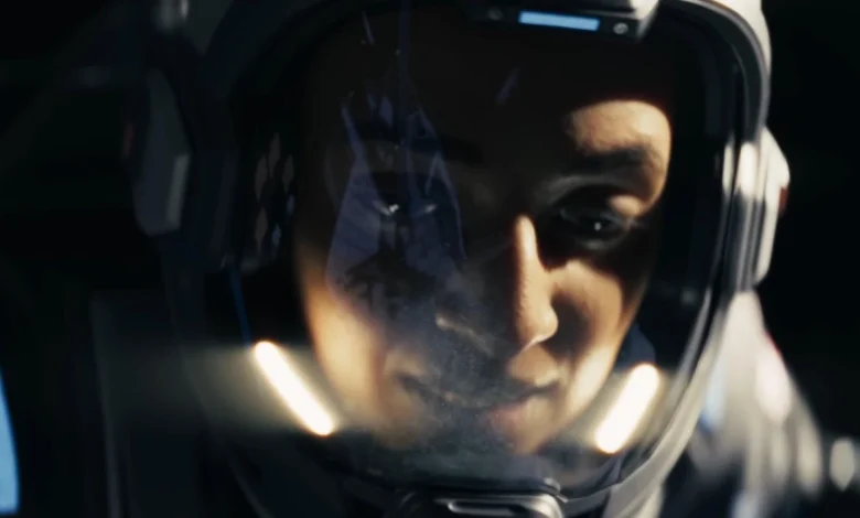 Close-up of an astronaut's focused face seen through the reflective visor of a futuristic space helmet.