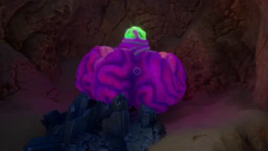 A large, purple brain-like growth with a glowing green topper sits on dark crystals inside a dimly lit rocky cave.