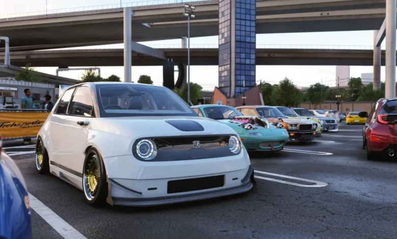 A modified white Honda e electric car is parked at an outdoor car meet beneath urban highway overpasses.