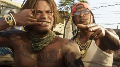 Two tattooed men with gold jewelry and grills pose confidently in a sun-drenched outdoor urban setting from the Grand Theft Auto VI trailer.