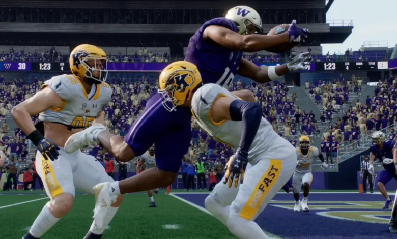 A Washington Huskies football player leaps to catch a pass over two Kent State defenders during a game in a crowded stadium.