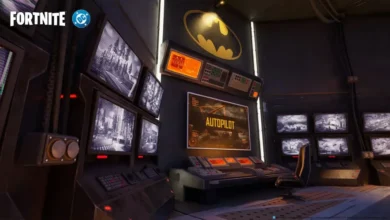 A high-tech Batcave command center in Fortnite featuring multiple surveillance monitors and a large yellow Batman logo on the wall.